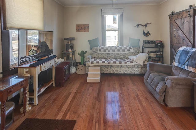 living area featuring ornamental molding, a barn door, and wood-type flooring