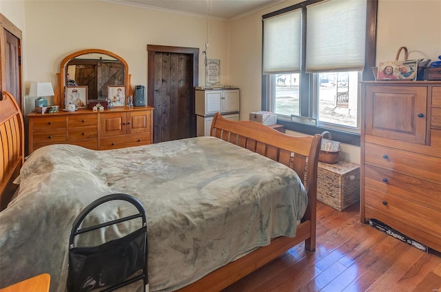 bedroom with crown molding and wood finished floors