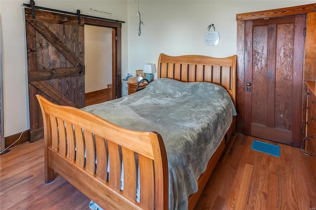 bedroom with a barn door and wood finished floors