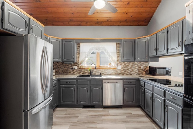 kitchen featuring gray cabinetry, a sink, wood ceiling, black appliances, and tasteful backsplash