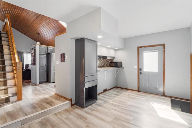 kitchen featuring a wealth of natural light, gray cabinets, backsplash, and freestanding refrigerator