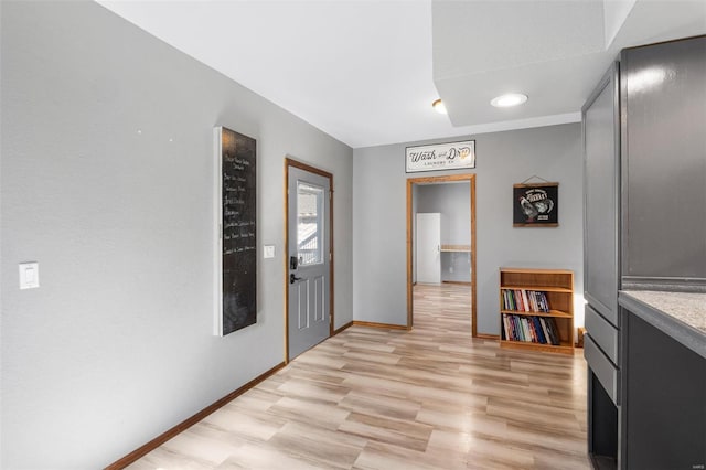 corridor with light wood-type flooring and baseboards