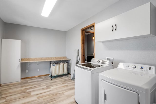 washroom with light wood-type flooring, cabinet space, and washer and clothes dryer