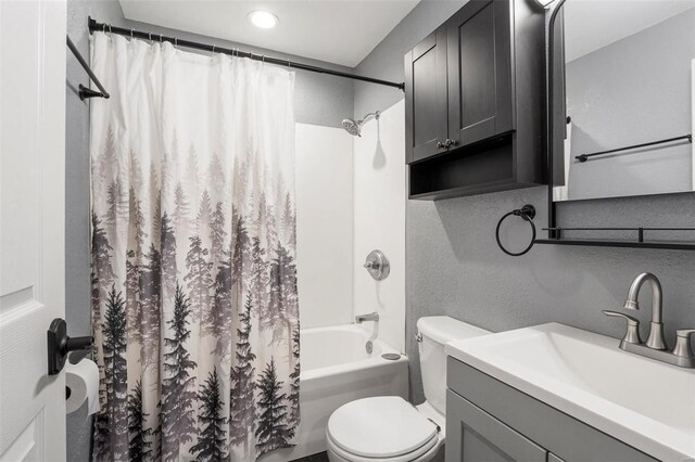 bathroom with a textured wall, shower / tub combo, vanity, and toilet