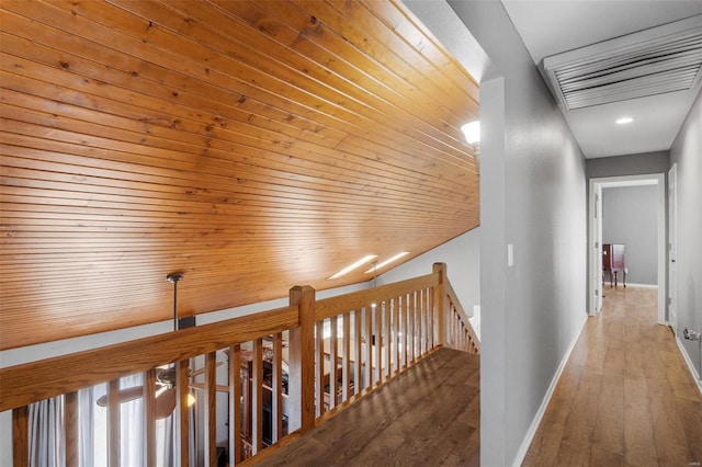 hallway with an upstairs landing, wood finished floors, wood ceiling, and baseboards