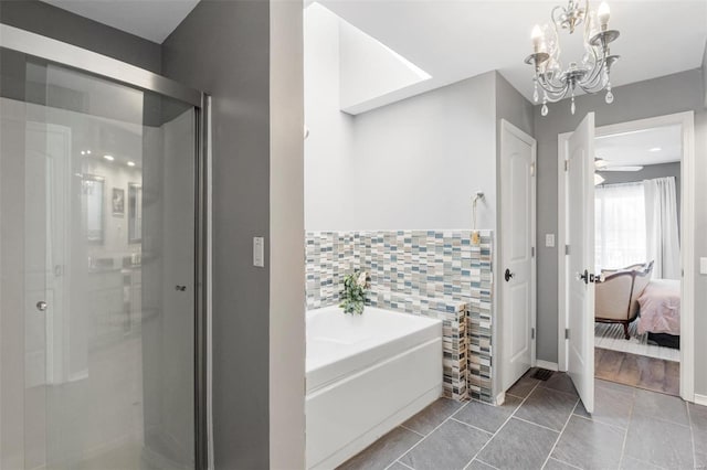 ensuite bathroom featuring ensuite bathroom, tile patterned flooring, a garden tub, tile walls, and an inviting chandelier