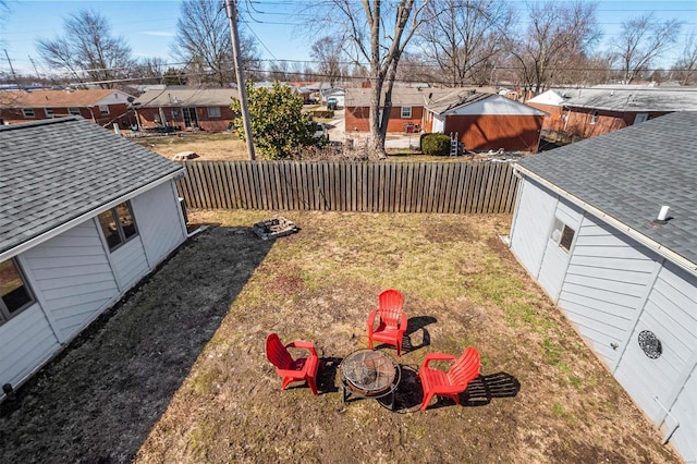 view of yard with a residential view, a fenced backyard, a fire pit, and an outbuilding