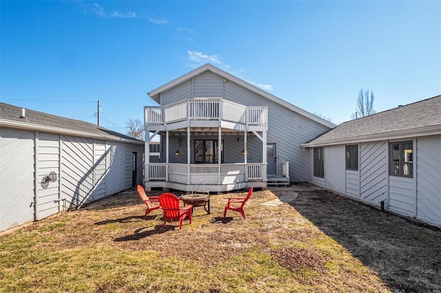 back of property with a fire pit, a wooden deck, and a balcony