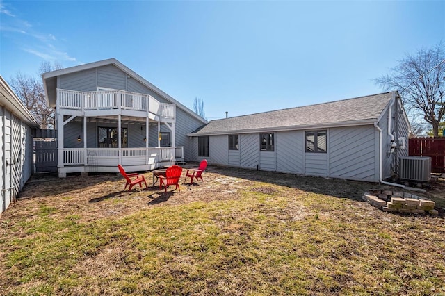 rear view of property with a shingled roof, central AC unit, fence, a balcony, and a fire pit