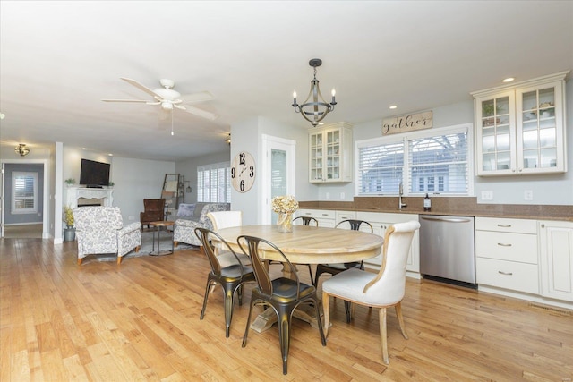 dining room featuring light wood-style floors, a fireplace, ceiling fan with notable chandelier, and recessed lighting