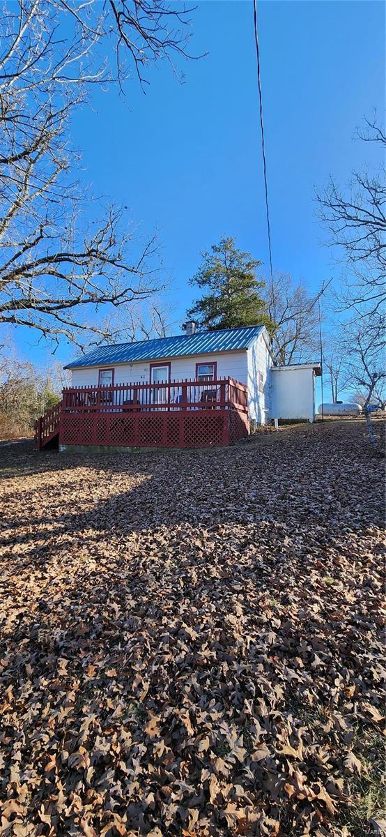 back of property featuring a deck and metal roof