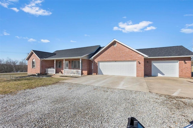 single story home with a porch, concrete driveway, brick siding, and a garage