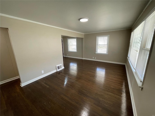 spare room with baseboards, dark wood-style flooring, visible vents, and crown molding