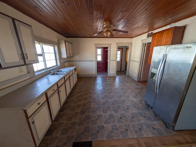 kitchen with light countertops, white cabinetry, a sink, wooden ceiling, and stainless steel fridge with ice dispenser