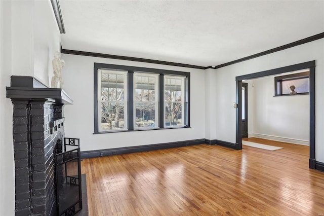 unfurnished living room featuring baseboards, a fireplace, hardwood / wood-style flooring, and crown molding