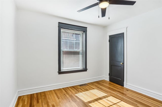 empty room with a ceiling fan, visible vents, baseboards, and wood finished floors