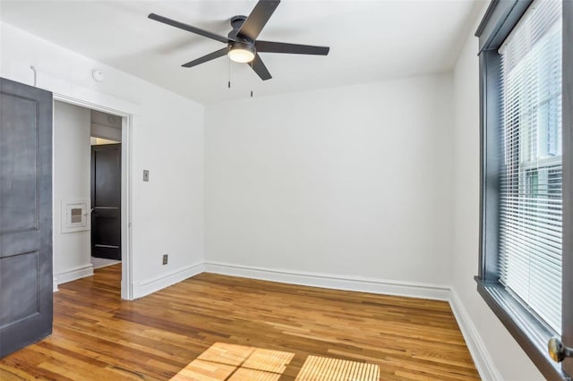 unfurnished room featuring ceiling fan, plenty of natural light, baseboards, and wood finished floors