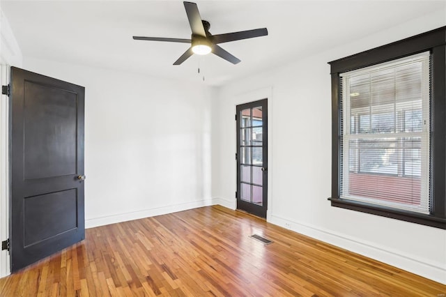 empty room featuring light wood finished floors, baseboards, visible vents, and ceiling fan