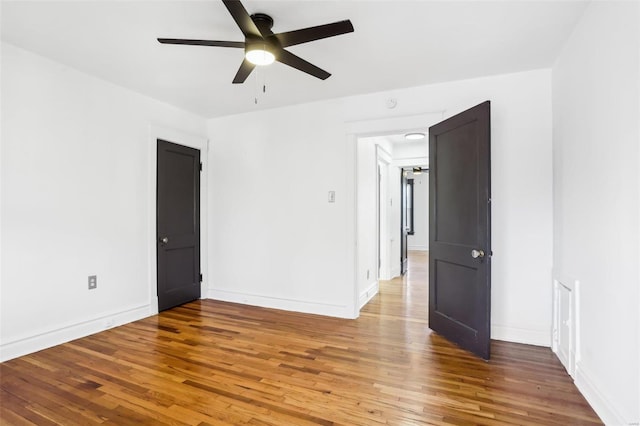 empty room with ceiling fan, baseboards, and wood finished floors