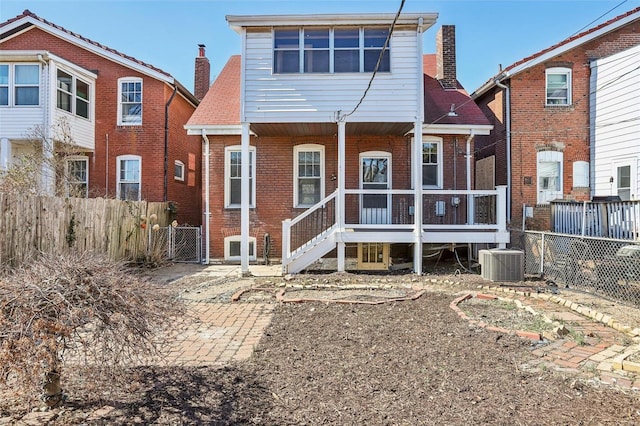 back of property with cooling unit, brick siding, fence, and a chimney