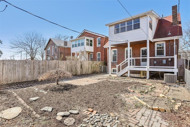 back of house featuring fence private yard, brick siding, a chimney, and central AC unit