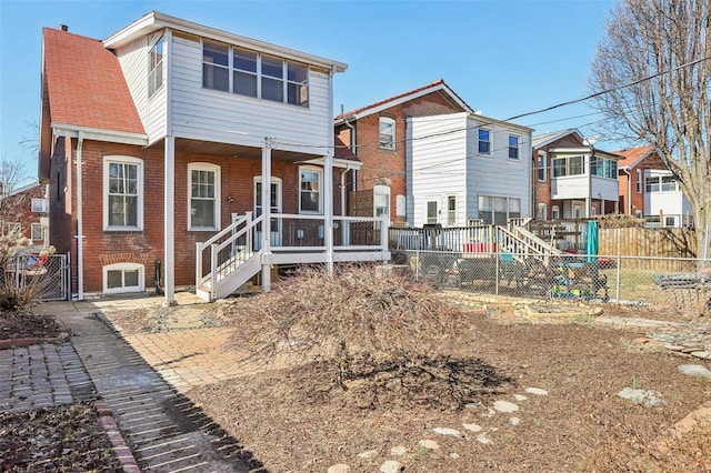 back of house with brick siding and fence