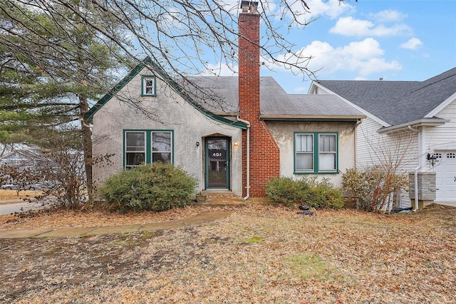 view of front of home with roof with shingles, a chimney, and stucco siding