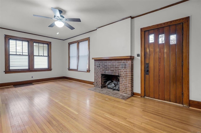 unfurnished living room with light wood-style flooring, a fireplace, visible vents, and ornamental molding