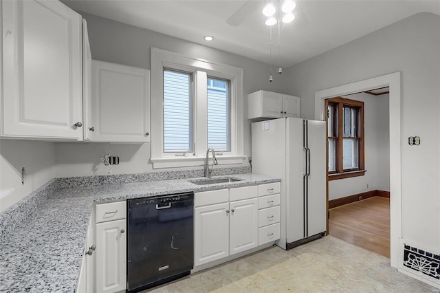 kitchen featuring black dishwasher, white cabinets, a sink, and freestanding refrigerator