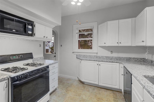 kitchen featuring arched walkways, black microwave, white cabinets, light stone countertops, and gas range oven