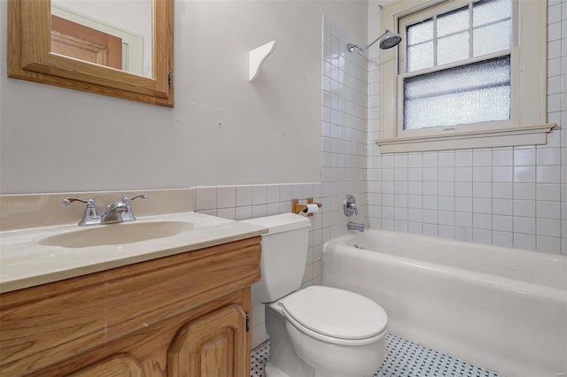 bathroom featuring toilet, tub / shower combination, tile walls, and vanity