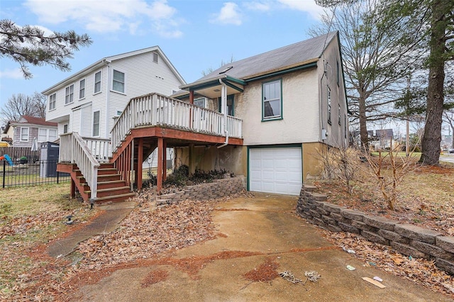 back of property with stucco siding, concrete driveway, stairway, an attached garage, and fence