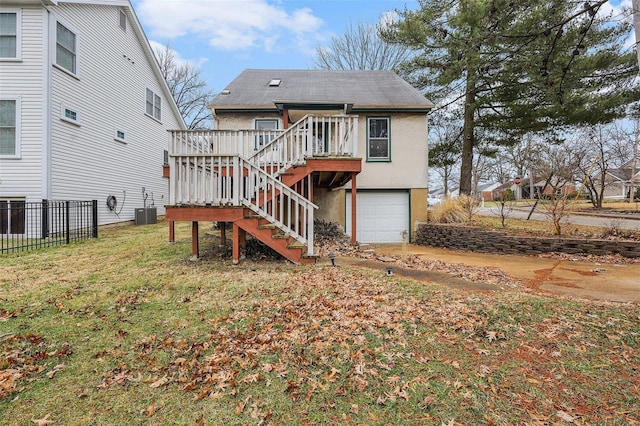 rear view of house with a garage, central AC unit, stairs, a yard, and stucco siding