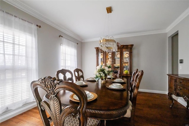 dining room with ornamental molding, a notable chandelier, baseboards, and wood finished floors