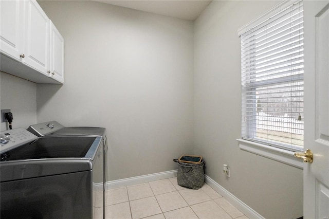 laundry area with a wealth of natural light, cabinet space, light tile patterned flooring, and separate washer and dryer