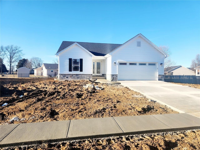 view of front facade featuring concrete driveway, stone siding, an attached garage, and fence