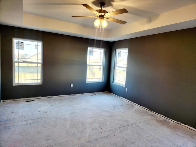 unfurnished room with a raised ceiling and a ceiling fan