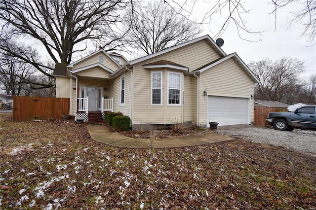 ranch-style home with a garage, gravel driveway, and fence