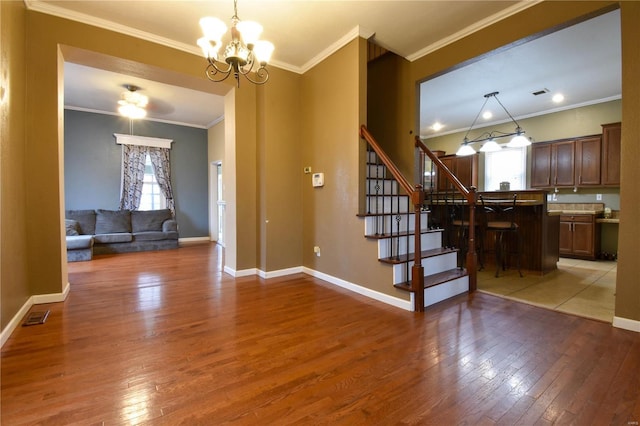 entryway with an inviting chandelier, light wood-style flooring, visible vents, and ornamental molding