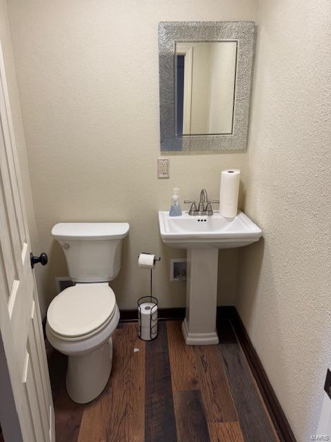 bathroom featuring toilet, baseboards, and wood finished floors