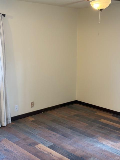 spare room featuring dark wood-style floors and baseboards