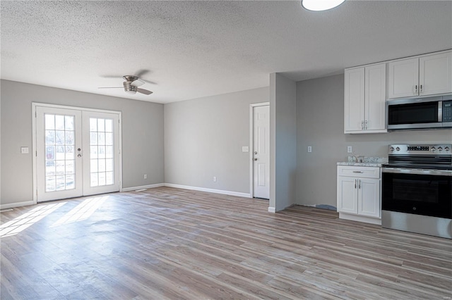 kitchen with stainless steel appliances, french doors, light wood-type flooring, and white cabinetry