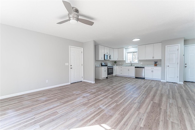 kitchen with appliances with stainless steel finishes, light countertops, a sink, and open floor plan