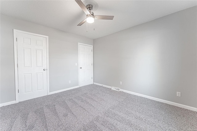 unfurnished bedroom with carpet floors, visible vents, a ceiling fan, a textured ceiling, and baseboards