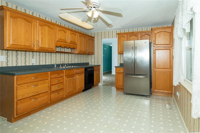 kitchen featuring wallpapered walls, dishwasher, brown cabinets, freestanding refrigerator, and a sink