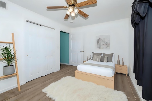 bedroom featuring baseboards, visible vents, a ceiling fan, wood finished floors, and a closet