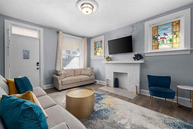 living room featuring a brick fireplace, wood finished floors, and baseboards