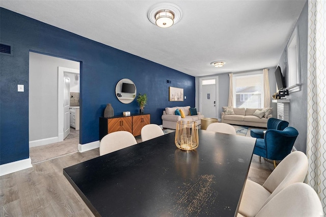 dining space featuring light wood-style floors, visible vents, and baseboards