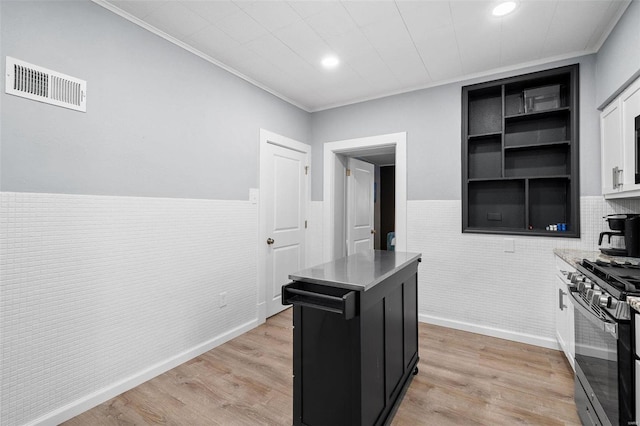 kitchen with visible vents, light wood-style flooring, dark cabinetry, white cabinetry, and gas stove