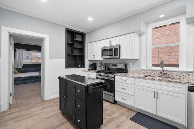 kitchen featuring a sink, white cabinetry, appliances with stainless steel finishes, dark cabinetry, and a center island